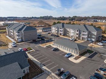A parking lot with cars and apartment buildings in the background.